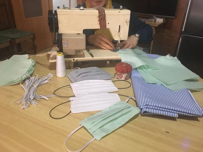 Una vecina cose mascarillas de tela