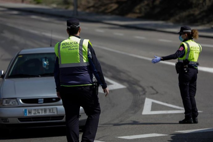 Dos agentes de la Policía Municipal protegidos con mascarillas regulan el tráfico en un control policial en el barrio madrileño de Vallecas durante una Semana Santa atípica en la que prosigue el estado de alarma decretado por el Gobierno para la lucha c