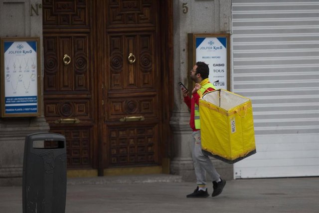 Un repartidor frente a un portal.