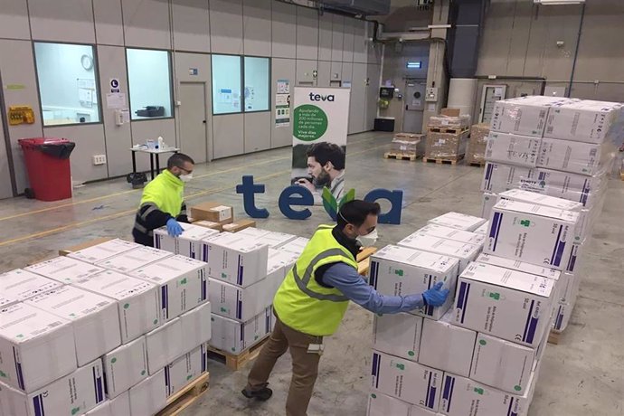 Dos trabajadores con mascarilla trabajan en el almacén de la compañía farmacéutica internacional TEVA  