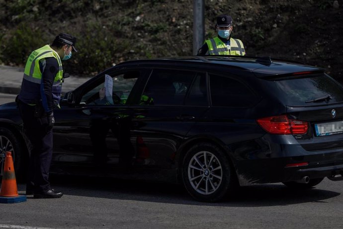 Dos agentes de la Policía Municipal protegidos con mascarillas piden a un conductor el justificante que le permite su salida de casa en un control policial de tráfico en el barrio madrileño de Vallecas.