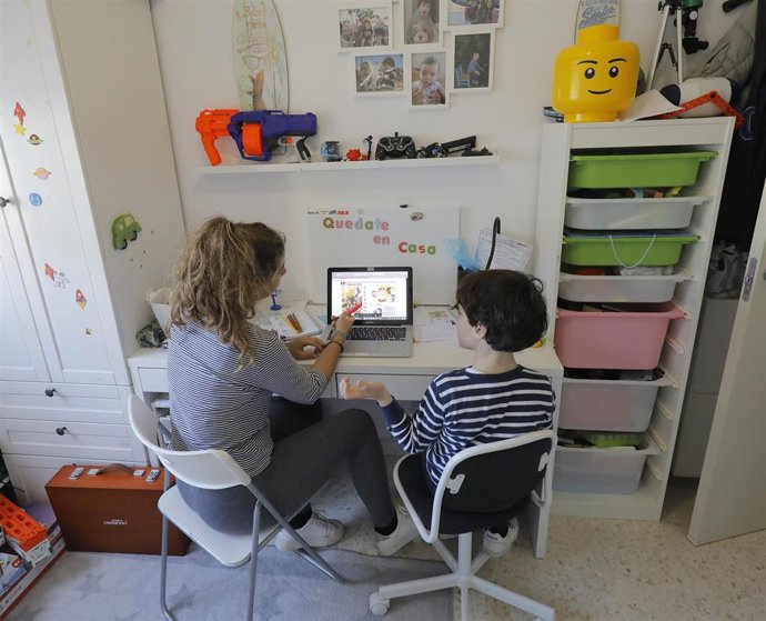 Una madre estudia con su hijo en casa.