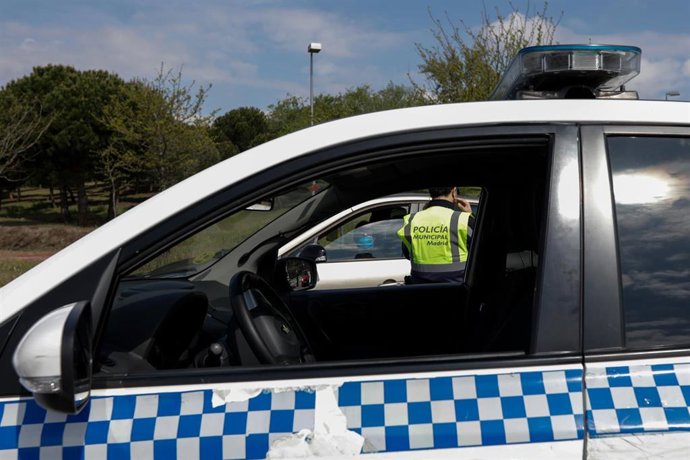 Un agente de la Policía Municipal pide a un conductor el justificante que le permite su salida de casa en un control policial de tráfico en el barrio madrileño de Vallecas.