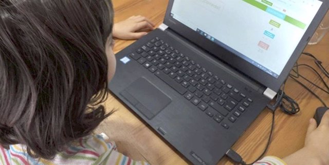 Una niña realizando tareas escolares desde un ordenador portátil