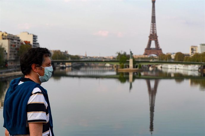 Un hombre con mascarilla cerca de la Torre Eiffel de París