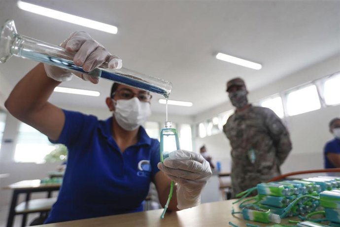 Una mujer rellena pequeños botes con desinfectante de manos en un centro sanitario de Lima, Perú.