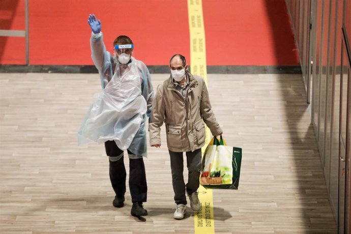 Un trabajador sanitario protegido acompaña por el interior del hospital de campaña montado en Ifema