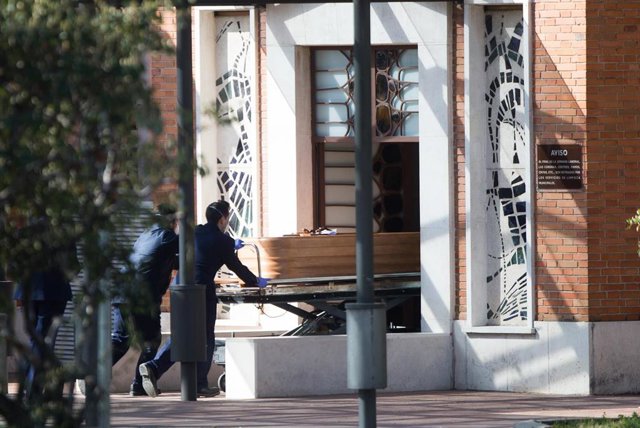 Dos trabajadores introducen un ataúd por la puerta de la funeraria municipal de Madrid