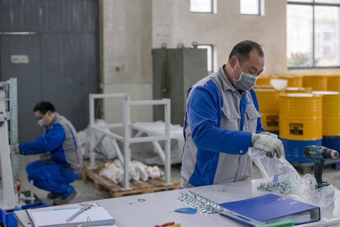 Operarios de una fábrica protegidos con mascarillas y guantes