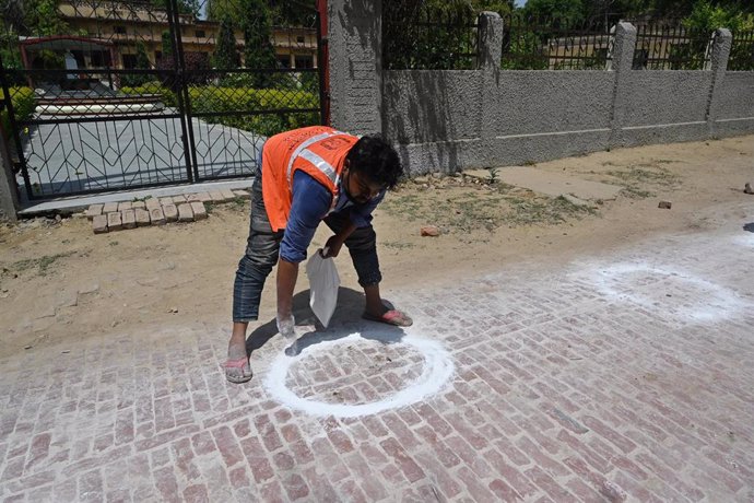 Un trabajador realiza marcas en el suelo para mantener la distancia social durante la crisis del coronavirus. 