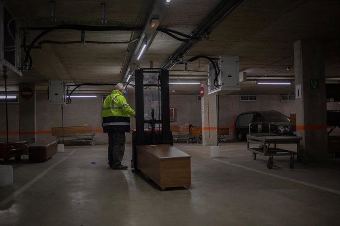 Un trabajador protegido con guantes y mascarilla en el tanatorio de campaña de Collserola situado en las dos plantas de parking del Tanatorio de Collserola. Con capacidad para albergar 1.800 cuerpos y con 5.000 metros cuadrados de extensión, es el tanat