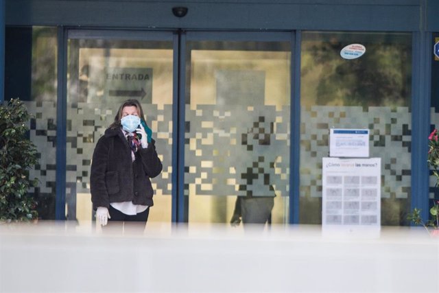 Una mujer protegida con mascarilla habla por teléfono al lado de la puerta de la Residencia para Mayores Ballesol Mirasierra 
