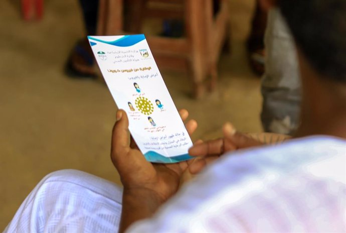 Un hombre mira un folleto informativo sobre la pandemia de coronavirus en Sudán