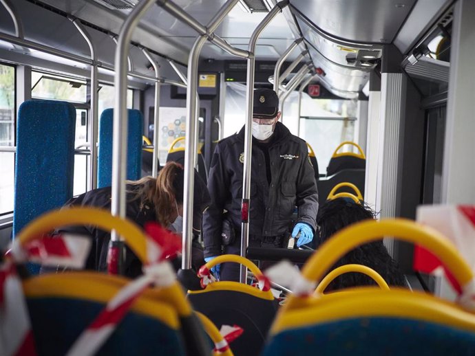 Dos agentes de la Policía Nacional protegidos con mascarillas identifican a viajeros de un autobús urbano en un control en la Avenida del Ejército de Pamplona durante el día en el que se reactiva la actividad laboral no esencial en las empresas cuyos em