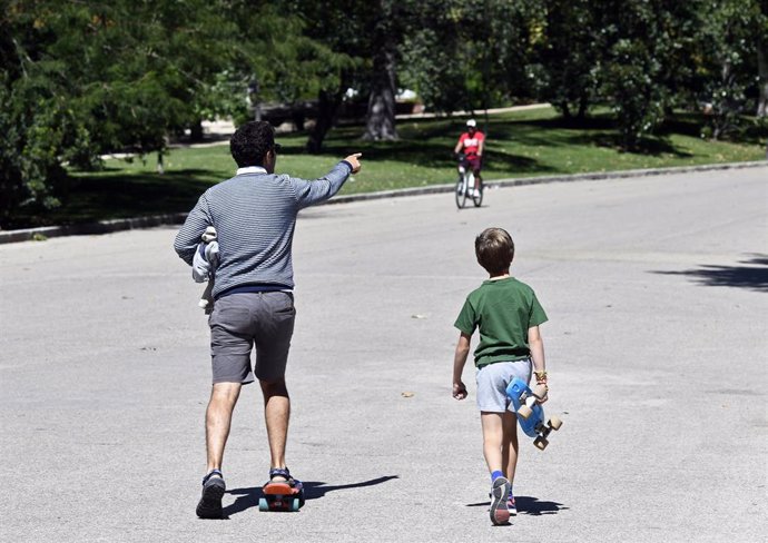 Un padre y un niño con, ambos con patinete, en un parque de Madrid en 2019.