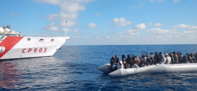 Patrullera de la Guardia Costera italiana junto a una lancha neumática con migrantes