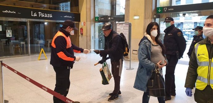 Agentes de la Policía entregan mascarillas en la estación de Oviedo, a 13 de marzo de 2020.