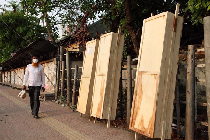 Un hombre camina por una calle de Dacca delante de varios ataúdes durante la pandemia de coronavirus