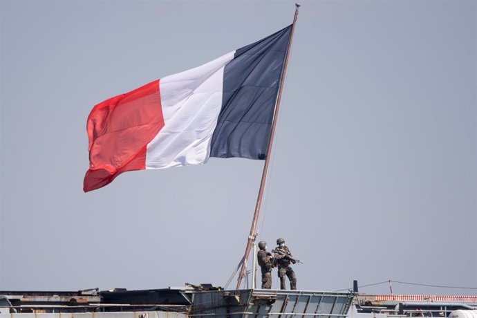 Militares con mascarilla junto a una bandera de Francia