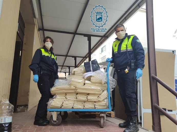 Dos policías locales de Málaga haciendo entrega de las batas para uso médico