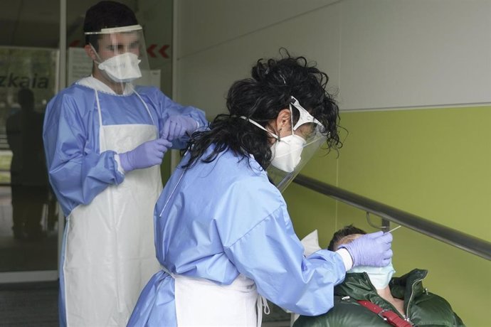 Dos sanitarios protegidos con guantes, mascarillas y pantallas protectoras recogen una muestra de una trabajadora funcionaria que ha dado positivo en Covid-19 o ha estado en riesgo de darlo, para realizar PCR en un local de la Diputación de Bizkaia