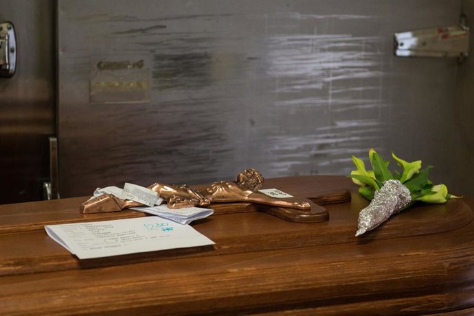 Detalle del crucifijo y flores sobre un féretro en la sala previa a la cremación en el Crematorio de la Almudena durante la pandemia de coronavirus en Madrid, España, a 13 de abril de 2020.