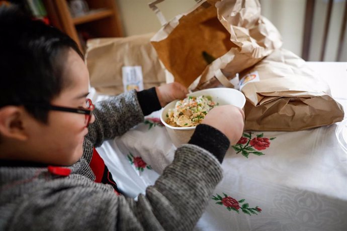 Un niño durante la comida en su casa del barrio madrileño de Carabanchel abre la tapa de un plato del menú de la ONG del chef José Andrés, que reparte en Madrid a las familias más necesitadas, a 14 de abril de 2020.