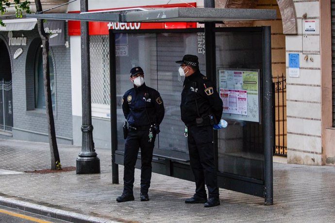 Policías nacionales se preparan en una parada de autobús para entregar mascarillas a los usuarios de transporte público.
