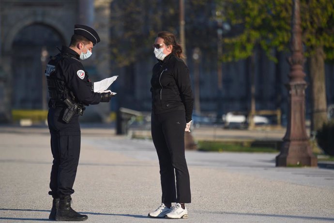 Policía de Francia comprueba el permiso de desplazamiento de una mujer durante el confinamiento a causa de la pandemia de coronavirus