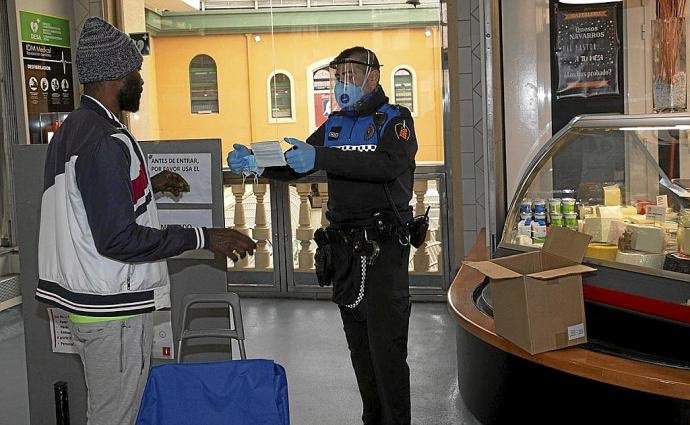 Un agente repartiendo mascarillas.