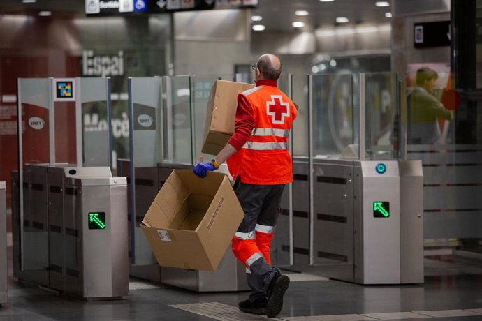 Un voluntario de Cruz Roja pasa por los tornos de la estación catalana de Diagonal con cajas vacías tras haber entregado mascarillas a los viajeros, en Barcelona (Catalunya, España), a 14 de abril de 2020.