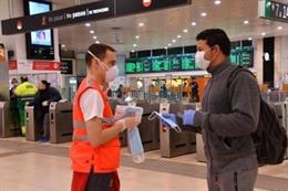 Un voluntario de la Creu Roja reparte mascarillas en la estación de Sants de Barcelona
