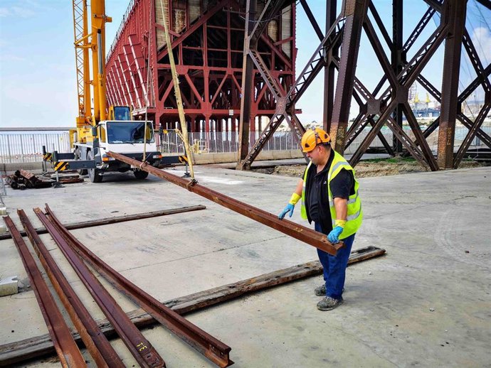 Un obrero carga vigas metálicas para la restaturación del Cable Inglés