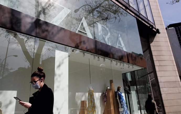 Una mujer con mascarilla pasa junto al escaparate de la tienda Zara de la Calle Princesa de Madrid del grupo Inditex, 