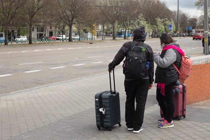 Dos turistas con maletas, uno de ellos con mascarilla, a su salida de la Estación de Atocha, durante el estado de alarma decretado por el coronavirus, en Madrid (España), a 16 de marzo de 2020.