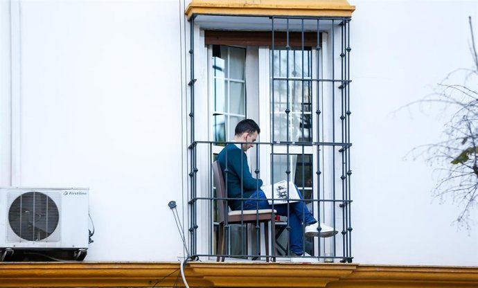 Un ciudadano aprovecha su minúsculo balcón para leer en la tercera semana de confinamiento por el coronavirus COVID 19. Sevilla a 03 de abril del 2020