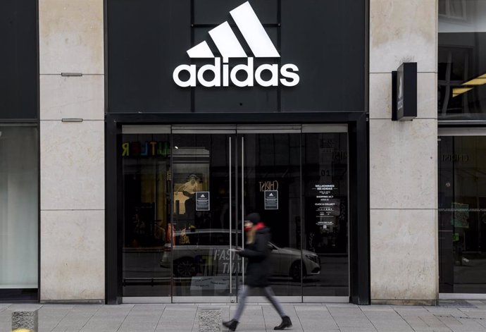 FILED - 01 April 2020, Hamburg: A woman walks in front of the closed entrance of a department store of the sporting goods manufacturer Adidas in downtown Hamburg. Adidas has received a 2.4-billion-euro (2.63-billion-dollar) loan from the state developme