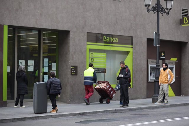 Varias personas esperan en una cola respectando la distancia de seguridad para entrar en una sucursal de Bankia de Madrid 