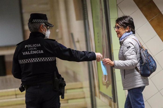 Agentes de policía local de Valencia entregan mascarillas en el metro durante el segundo día de reparto de mascarillas en el transporte público