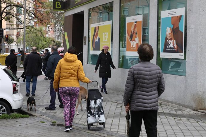 Personas en fila guardan su turno para entrar en una oficina de Bankia. En Madrid (España), a 1 de abril de 2020.