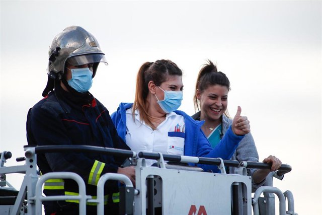 Un bombero sube a dos sanitarias a la cesta del camión durante el homenaje diario a los sanitarios en el Hospital Infanta Elena de Valdemoro como consecuencia de la pandemia de coronavirus en Valdemoro, Madrid, España, a 13 de abril de 2020.