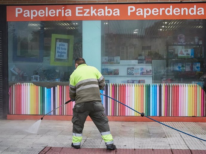 Un operario de limpieza desinfecta el exterior de un comercio de primera necesidad durante la cuarta semana del estado de alarma, en Pamplona (Navarra) a 6 de abril de 2020.