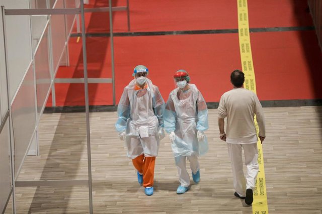 Trabajadores sanitarios protegidos caminan por el interior del hospital de campaña montado en IFEMA.