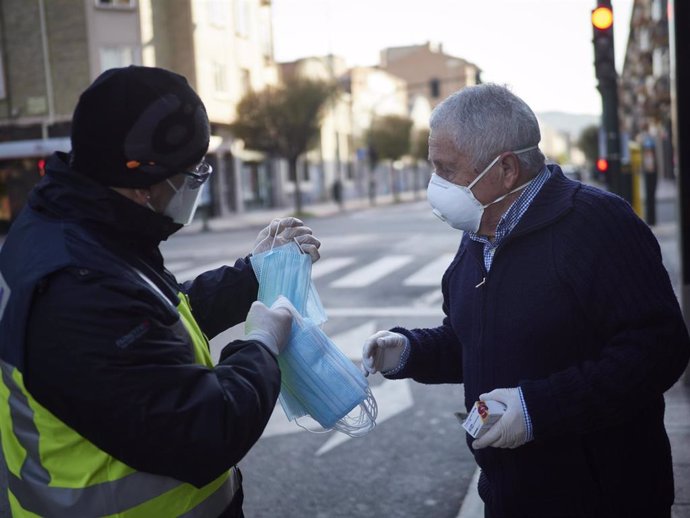 Un agente de la Policía Nacional reparte una mascarilla a un hombre  en Pamplona/Navarra (España) a 15 de abril de 2020.