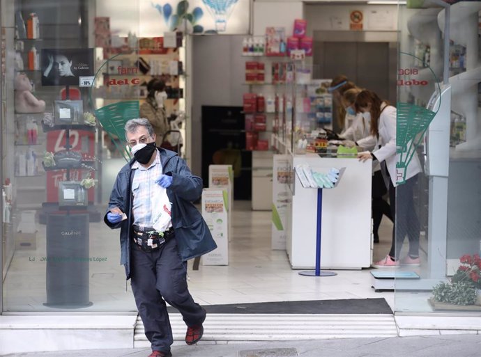 Un hombre protegido con mascarilla y guantes sale de una Farmacia. En Madrid (España) a 14 de abril de 2020.
