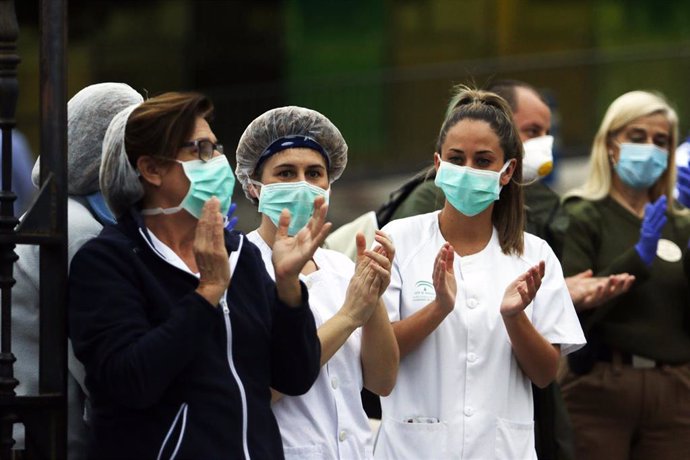 Bomberos realizan junto a trabajadores de Correos el aplauso a los sanitarios, en la puerta principal del Hospital Regional de Málaga.