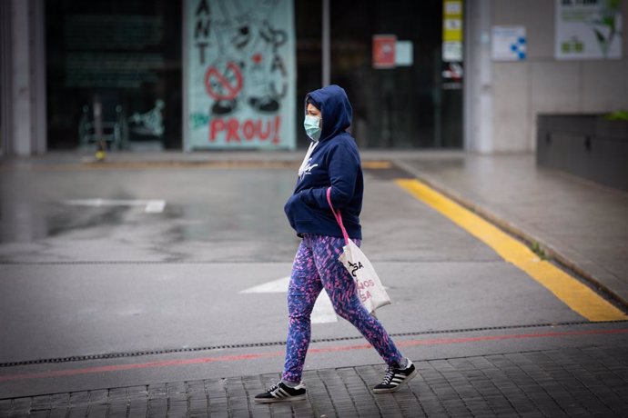 Una dona passa pels voltants de l'Estació de Barcelona Sants durant el dia en el qual entra en vigor la limitació total de moviments salvo dels treballadors d'activitats essencials, mesura adoptada ahir pel Govern com a prevenció del