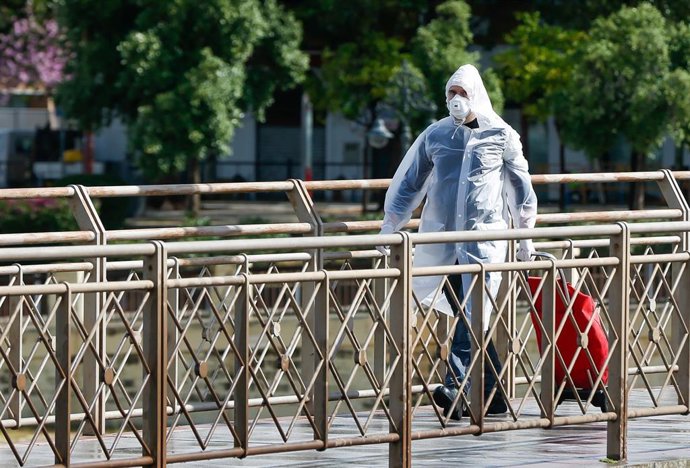 Peatón por el puente de San Telmo en una mañana de tormentas y lluvias en la quinta semana del estado de alarma por el coronavirus COVID-19. Sevilla a 15 de abril 2020