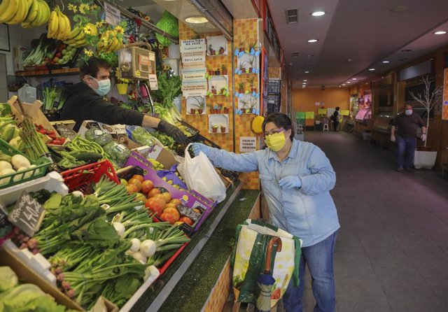 Una mujer protegida con mascarilla compra en una frutería del mercado de Nervión durante la quinta semana del estado de alarma por la crisis del coronavirus, (Covid-19). En Sevilla, (Andalucía, España), a 15 de abril de 2020.