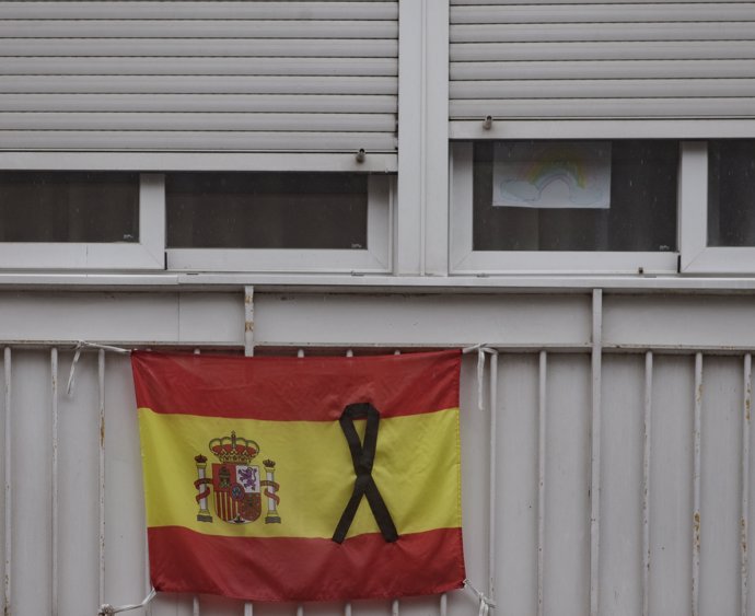 Una bandera de España colgada en un balcón con un crespón negro en recuerdo a los fallecidos por Covid-19.